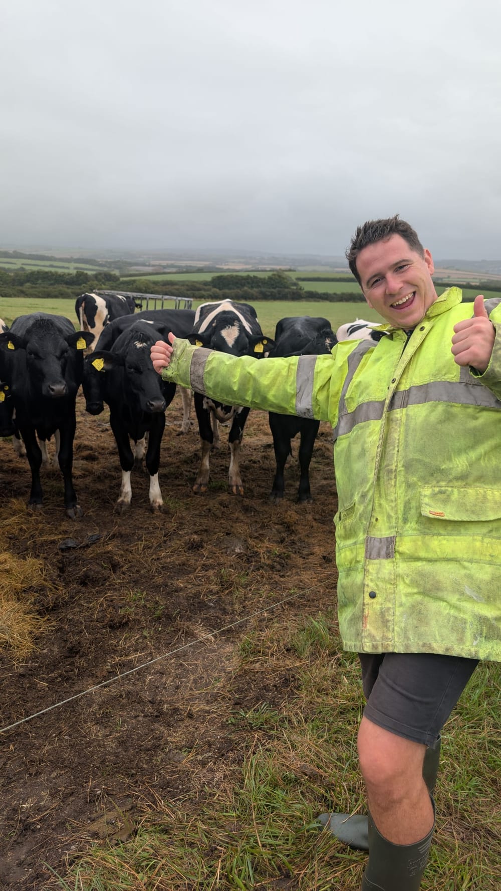 Archie giving a thumbs up beside a herd of cows in Cornwall, from his farming days